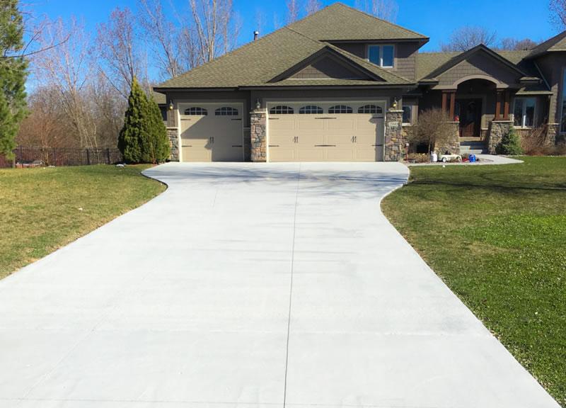 Bright, freshly cleaned concrete driveway in front of a home.