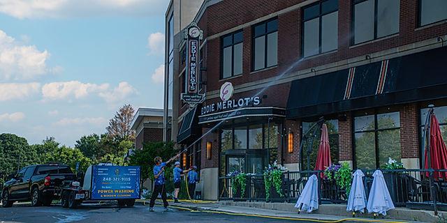 Crew pressure washing a commercial restaurant storefront and entry.