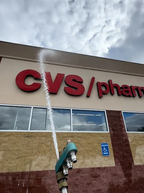 High-pressure water washing the exterior signage and facade of a CVS Pharmacy storefront.