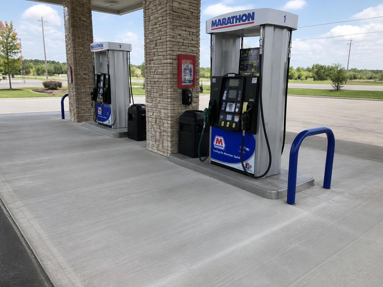 The same commercial gas station fuel island with spotless, freshly degreased concrete after pressure washing.